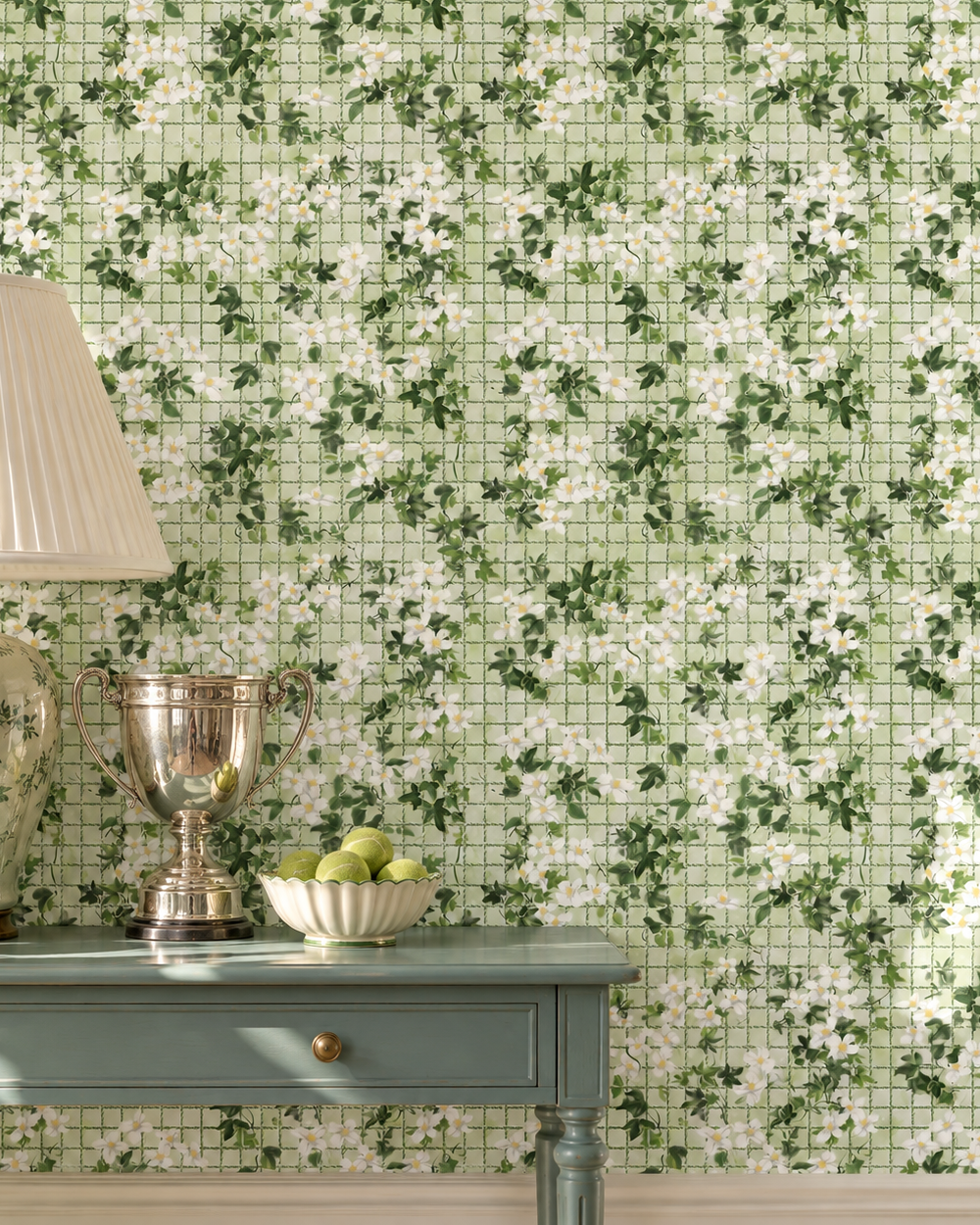 Green and white floral mosaic tile wallpaper shown on a wall in a styled room setting with a light blue console table, a silver trophy, and a lamp. Performance vinyl wallpaper with watercolor ivy, white flowers, and a subtle tennis-net grid on a textured, washable surface in a fresh garden green color great for bathrooms, locker rooms because it is moisture resistant