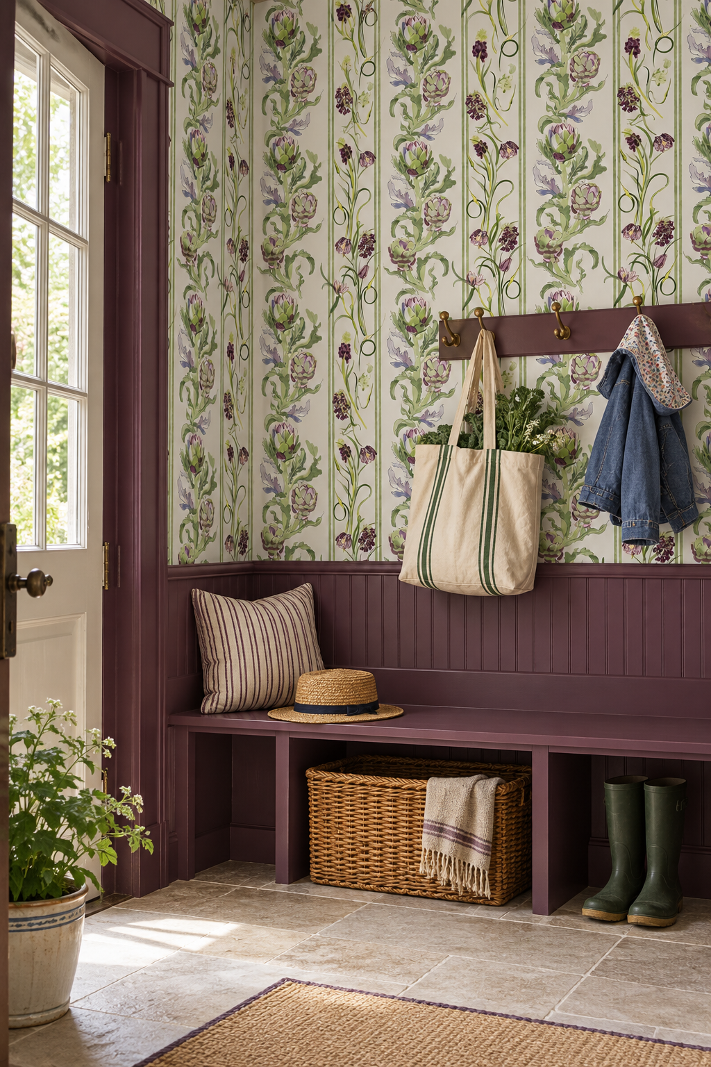 A styled mudroom showing wallpaper with a repeating vertical floral and thistle pattern in green, purple, and lavender on a light background, above a sage green cabinet with a cream countertop and a small gold bowl. artichoke wallpaper, botanical stripe wallpaper, green stripe wallpaper, vegetable wallpaper, farmers market wallpaper, kitchen wallpaper, green floral wallpaper, striped botanical print, traditional matte wallpaper, all-natural eco-friendly wall-cover, custom wallpaper luxury wallpaper