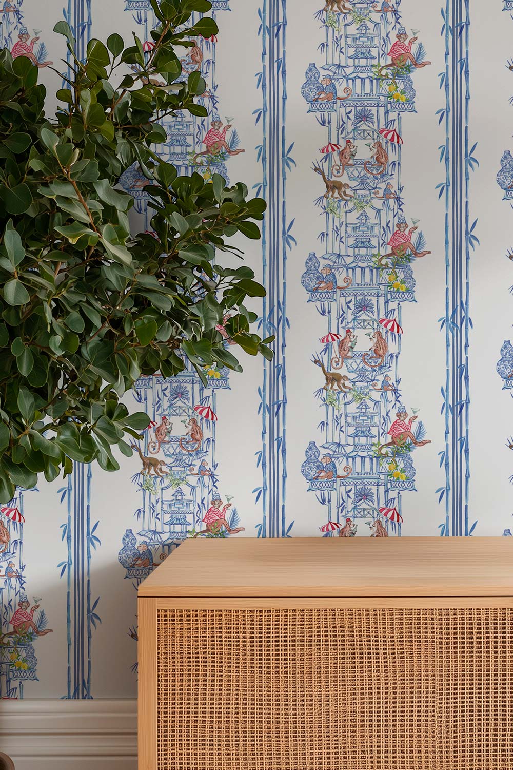 Hand-painted chinoiserie toile wallpaper on natural grasscloth featuring monkeys, pagodas, bamboo stripes, and whimsical party scenes in multiple colorways.