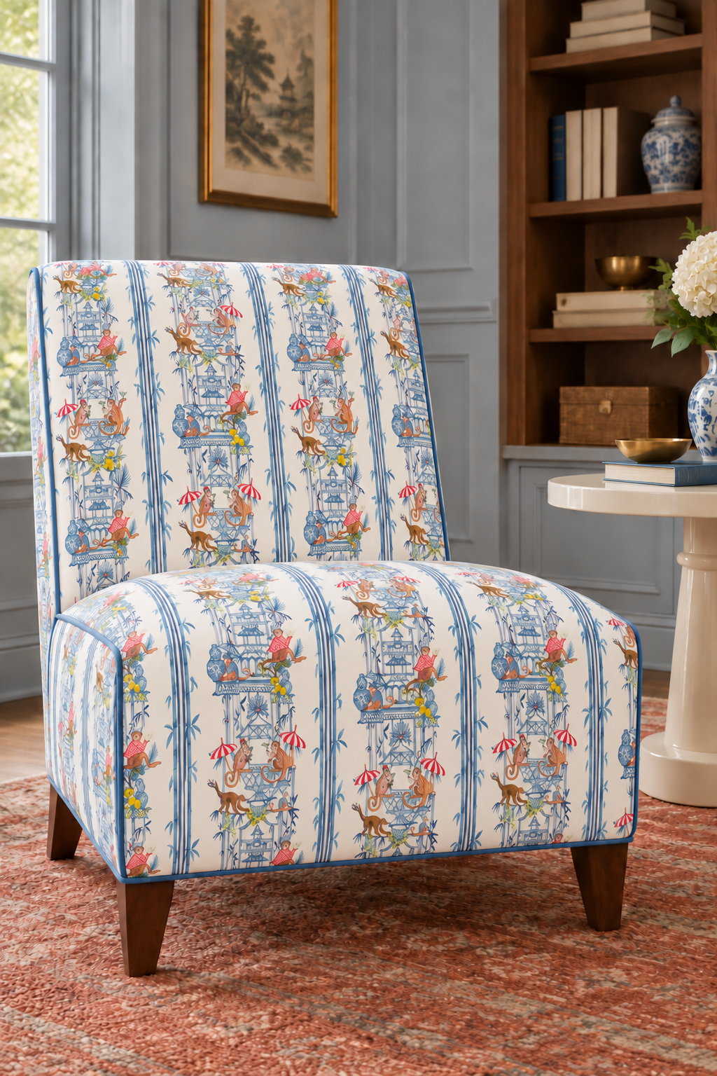 Whimsical chinoiserie toile upholstery fabric featuring pagodas, bamboo details, and monkeys partying in a hand-painted striped layout featured as upholstery on this traditional slipper chair in this formal living room