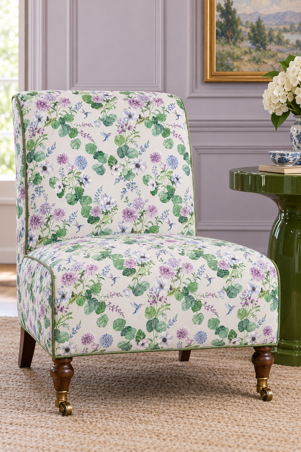 Botanical floral upholstery fabric with hand-painted dahlias, snapdragons, and hummingbirds in a vibrant, garden-inspired layout featured as the upholstery on this traditional slipper chair in this formal living room.