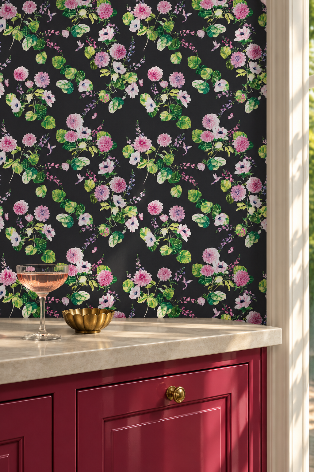 A close-up of floral wallpaper with pink and white flowers and green leaves on a black background, installed above a red cabinet with a marble countertop and a glass of rosé wine. Chirp Society Garden grasscloth wallpaper with hand-painted dahlias, scabiosa, snapdragons, and hummingbirds in a vibrant watercolor botanical design on all natural and eco-friendly grass cloth wall covering perfect for luxury guest bedooms