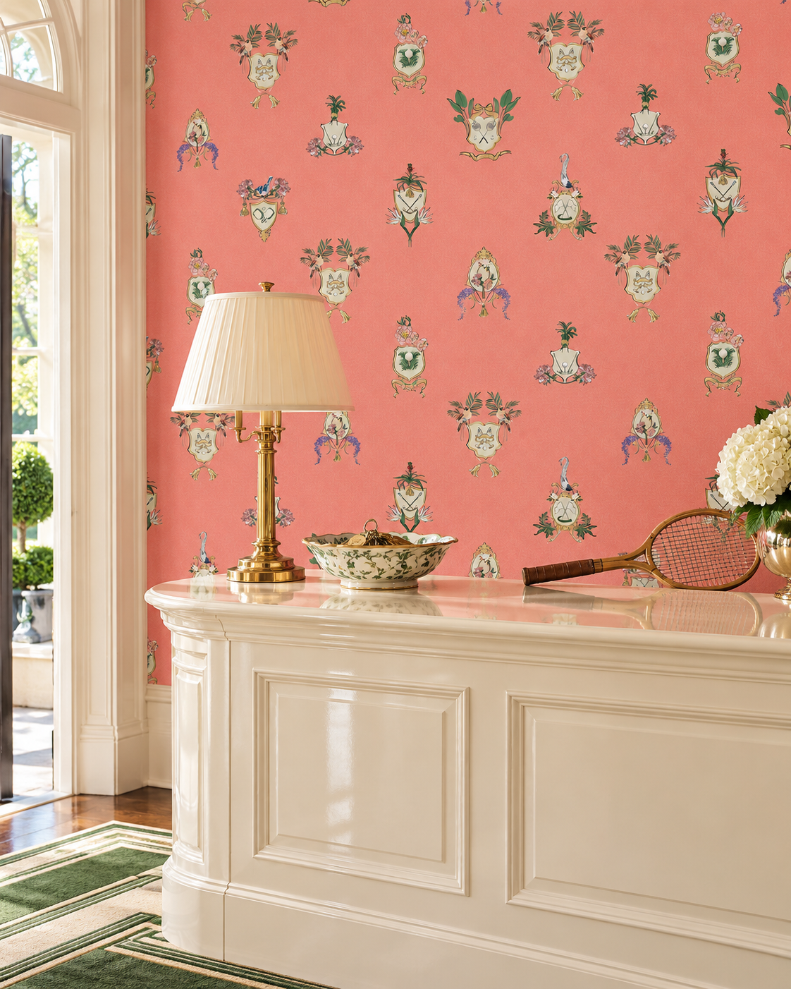 Country Club Crests traditional matte wallpaper with hand-painted tennis, golf and paddle crests, birds and florals on an bright coral background.
