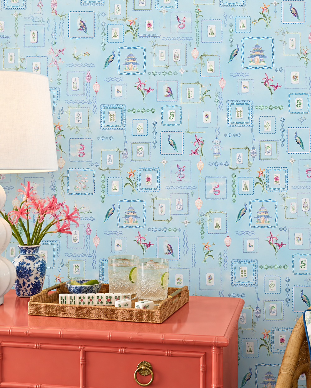 A living room featuring light blue wallpaper with a delicate vintage floral and architectural pattern. Washable performance vinyl Mahjong Tiles wallpaper with hand-painted chinoiserie details, perfect for powder rooms, bathrooms, game rooms, and clubs.