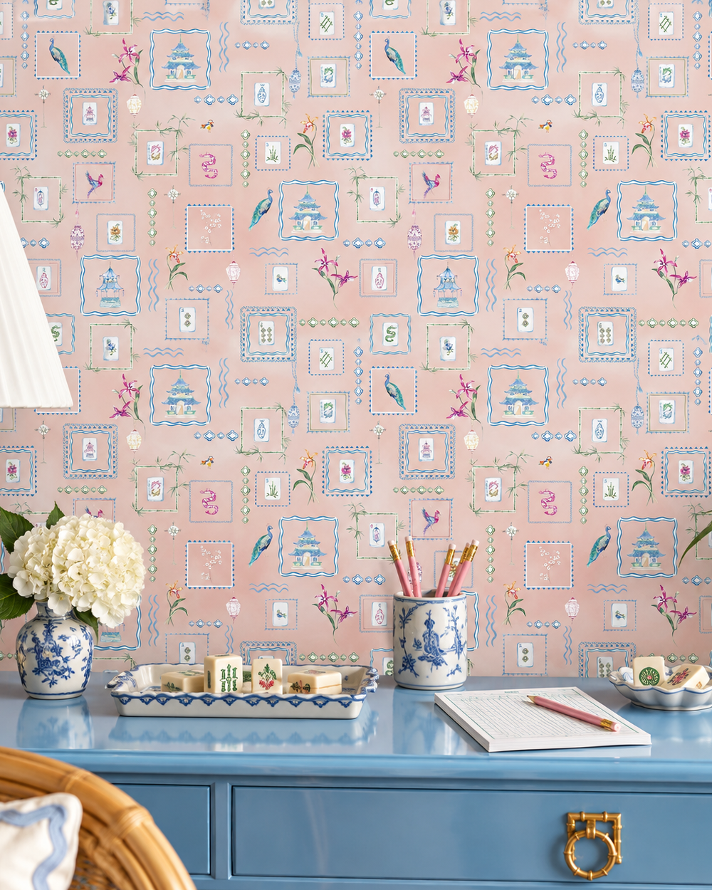 Hand-painted watercolor Mahjong Tiles wallpaper featuring mahjong tiles, pagodas, bamboo, birds, ginger jars, lanterns, and chinoiserie artwork on a soft pink coral background printed on an all-natural and eco-friendly grasscloth wall-covering.