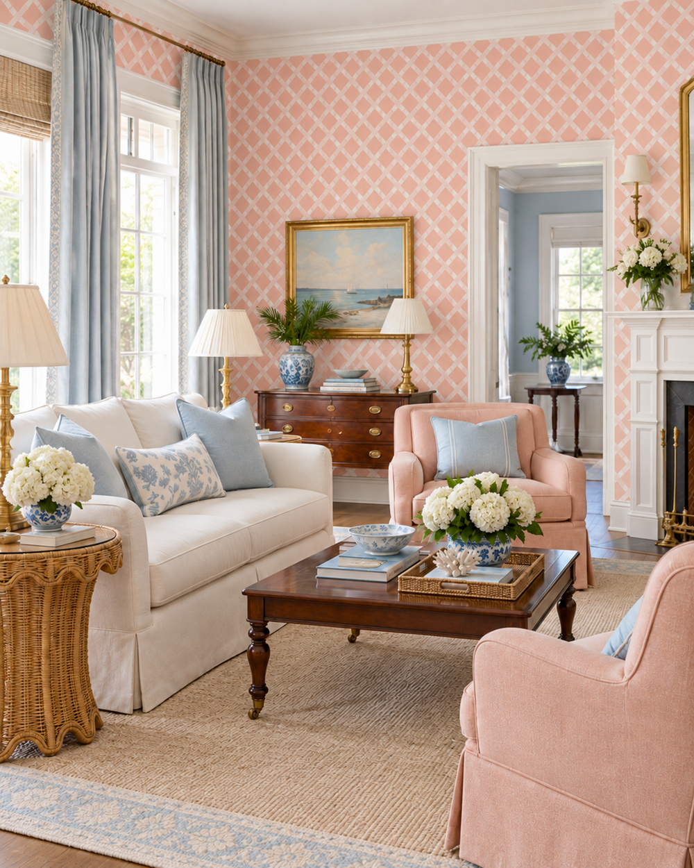 A beautifully styled living room featuring pink patterned wallpaper, a cream sofa with blue pillows, a pink armchair, a dark wood coffee table, and a beige jute rug.
