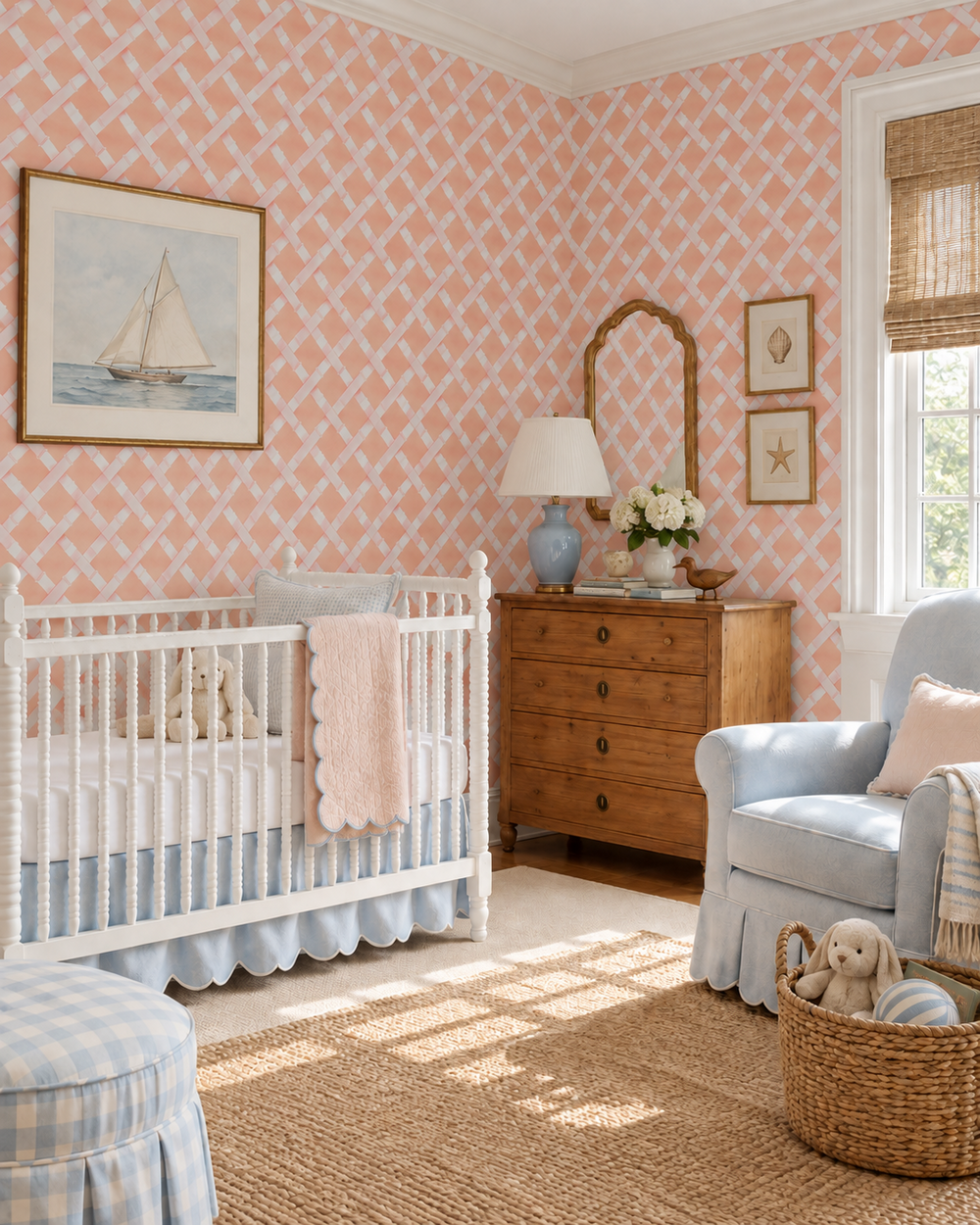 A styled nursery room featuring pink and white geometric wallpaper, a white wooden crib with a light blue skirt, a light blue armchair, a wooden dresser, and a natural jute rug.
