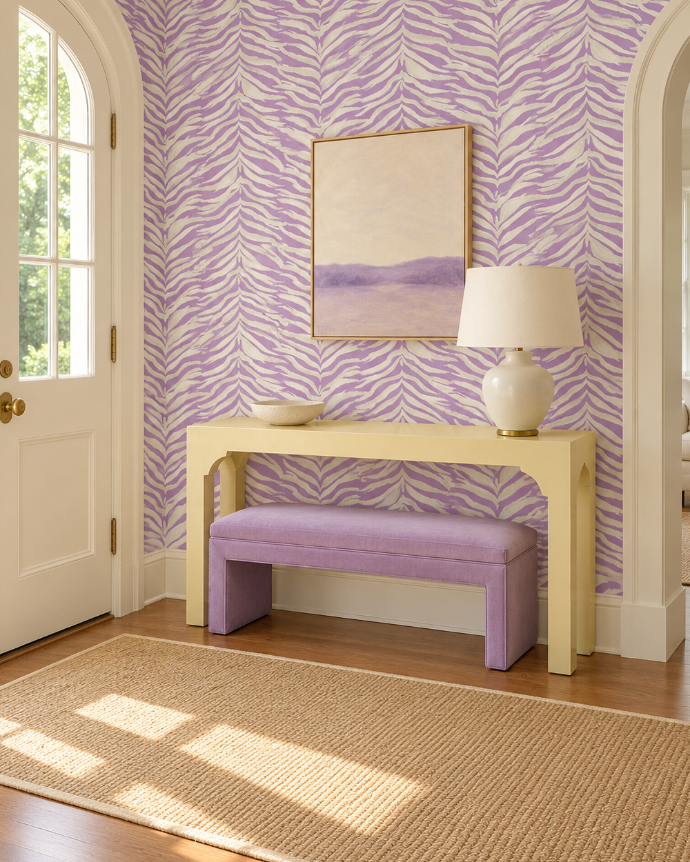 A styled interior entryway featuring lavender and white zebra-patterned wallpaper, a light wood console table, a lavender upholstered bench, a white table lamp, a beige woven rug, and a framed abstract landscape painting on the wall. feminine purple and white watercolor zebra stripe printed on commercial grade water and stain resistant performance vinyl wall-covering, great for bathrooms, kitchens and high traffic spaces